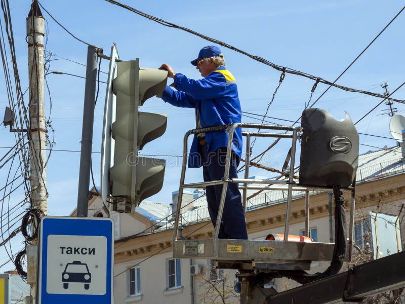 The employee of city services serves a traffic light on Lenin`s area of the city of Voronezh. Voronezh, Russia - April 27, 2017: The employee of city services stock photos The employee of city services serves a traffic light on Lenin`s area of the city of Voronezh. Voronezh, Russia - April 27, 2017: The employee of city services stock photos