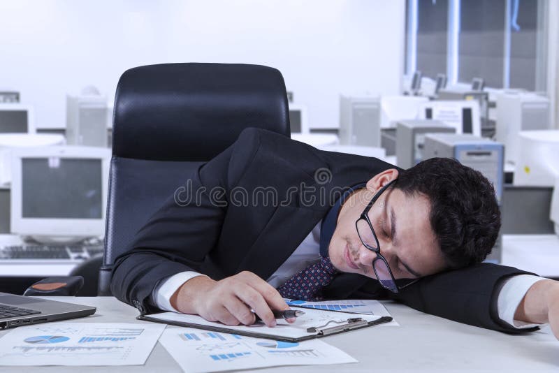 Young businessperson sleeping in the office with paperwork on the table. Young businessperson sleeping in the office with paperwork on the table