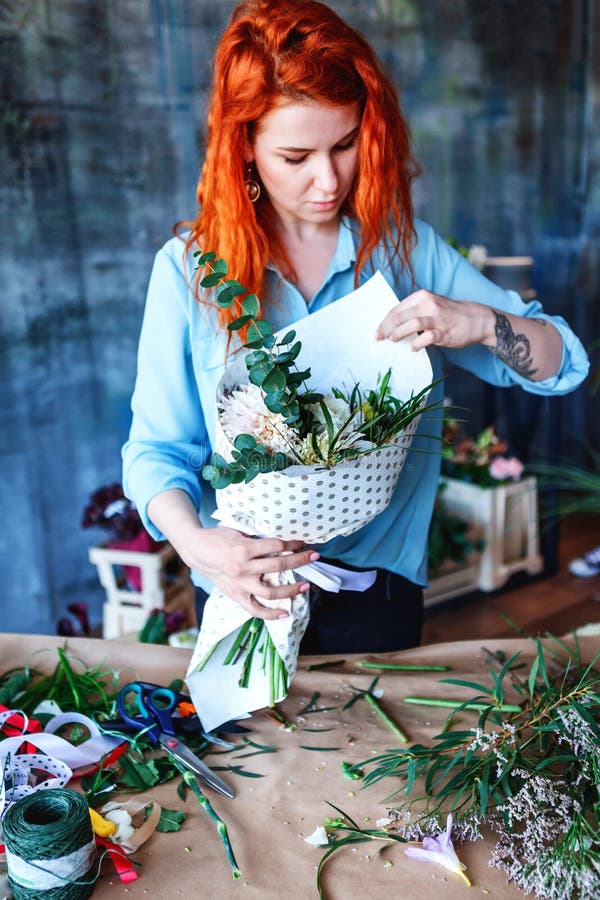 Employé de magasin féminin gai avec du charme faisant le bouquet avec le crocus pourpre, le populus d'eucalyptus et le singl popl