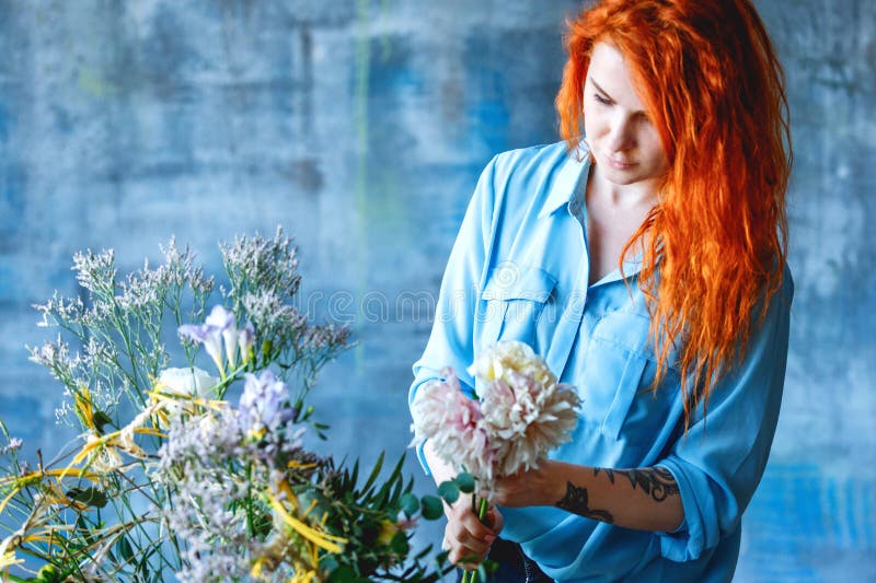 Employé de magasin féminin gai avec du charme faisant le bouquet transparent de carcasse avec le populus et le chrysanthème popla