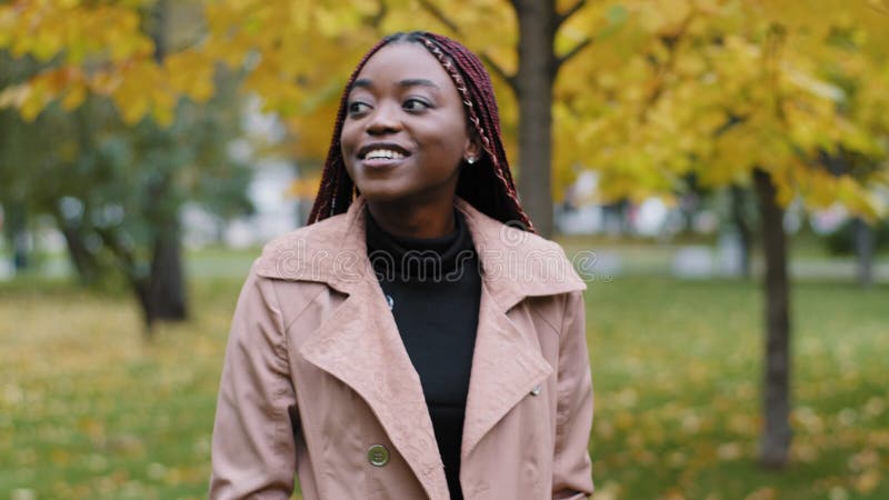 Employé(e) femme à l'extérieur. sourire joyeuse rêve afro-américaine jeune femme marchant dans le parc de la ville à clips vidéos