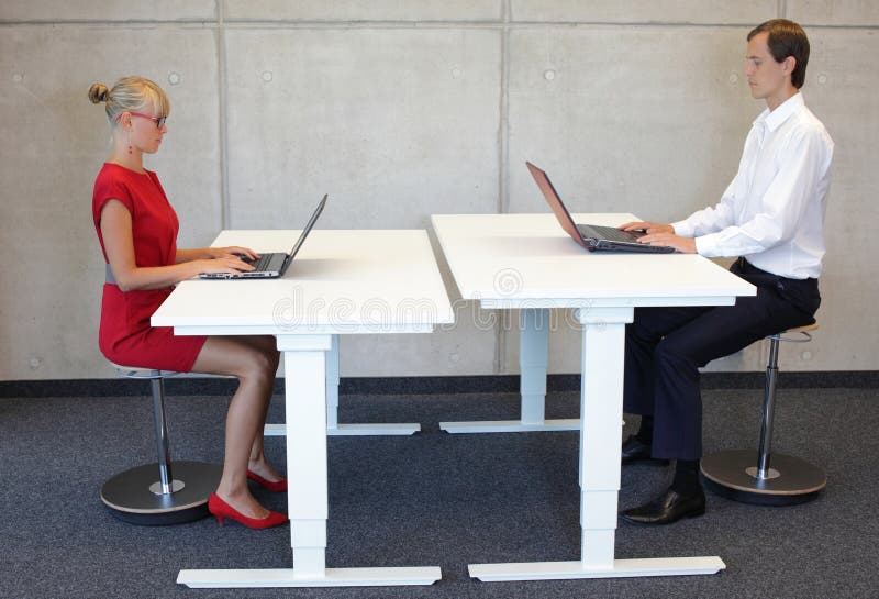 Employés de bureau dans la position d'assise correcte aux bureaux avec des ordinateurs portables photo libre de droits Employés de bureau dans la position d'assise correcte aux bureaux avec des ordinateurs portables photo libre de droits