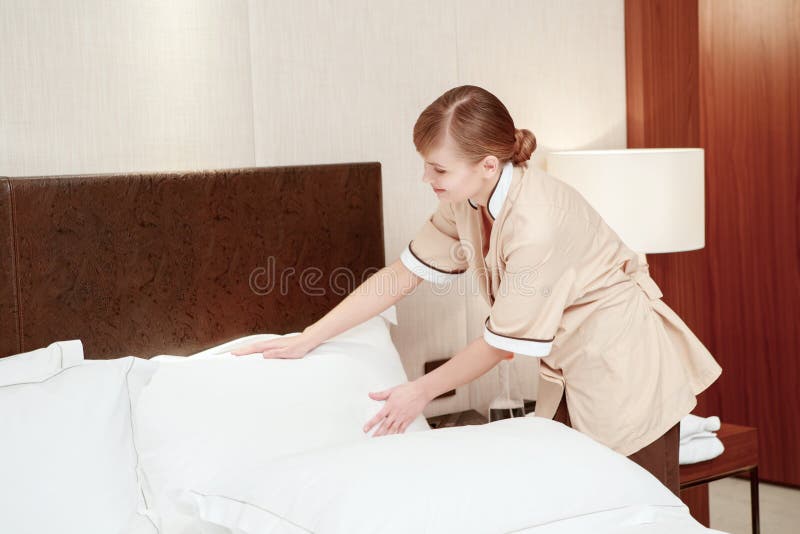A empregada doméstica muda o roupa de cama no hotel foto de stock A empregada doméstica muda o roupa de cama no hotel foto de stock