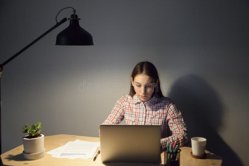 Empregado adulto novo que faz o relatório da noite atrasada imagem de stock royalty free Empregado adulto novo que faz o relatório da noite atrasada imagem de stock royalty free