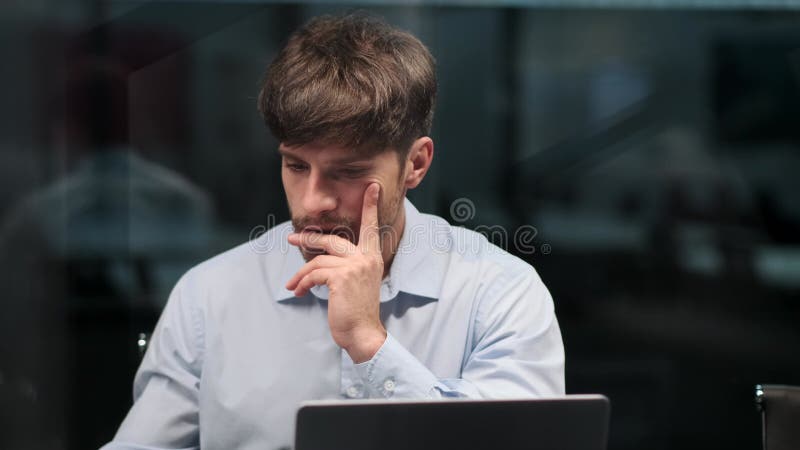 Emprendedor contemplativo trabajando con laptop y papeles en la oficina