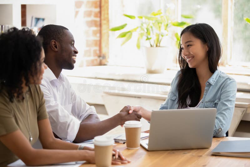 Empresaria asiática del apretón de manos africano del hombre de negocios que agradece por buen trabajo imagenes de archivo Empresaria asiática del apretón de manos africano del hombre de negocios que agradece por buen trabajo imagenes de archivo