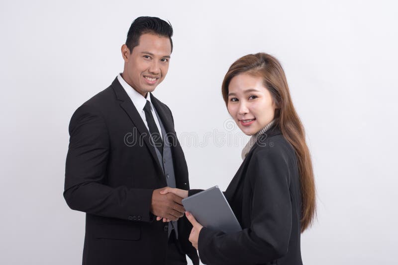 Empresaria asiática profesional que hace el apretón de manos con un hombre de negocios y que mira la cámara imagen de archivo libre de regalías Empresaria asiática profesional que hace el apretón de manos con un hombre de negocios y que mira la cámara imagen de archivo libre de regalías