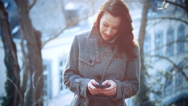 Empresaria atractiva al aire libre con el teléfono móvil