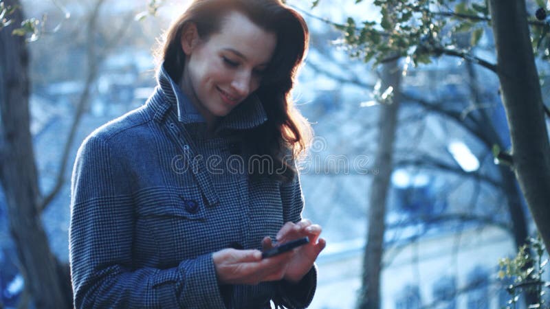 Empresaria atractiva al aire libre con el teléfono móvil