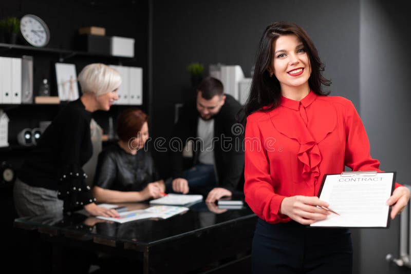 Empresaria con la pluma y contrato en el fondo de los oficinistas discutir el proyecto imagen de archivo libre de regalías Empresaria con la pluma y contrato en el fondo de los oficinistas discutir el proyecto imagen de archivo libre de regalías