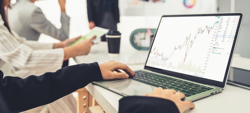 Empresaria en el análisis de datos del mercado de valores mediante ordenador portátil. Empresaria en el análisis de datos del mercado de valores usando computadora portátil en la oficina mientras asiste a una reunión de grupo con el equipo de negocios.