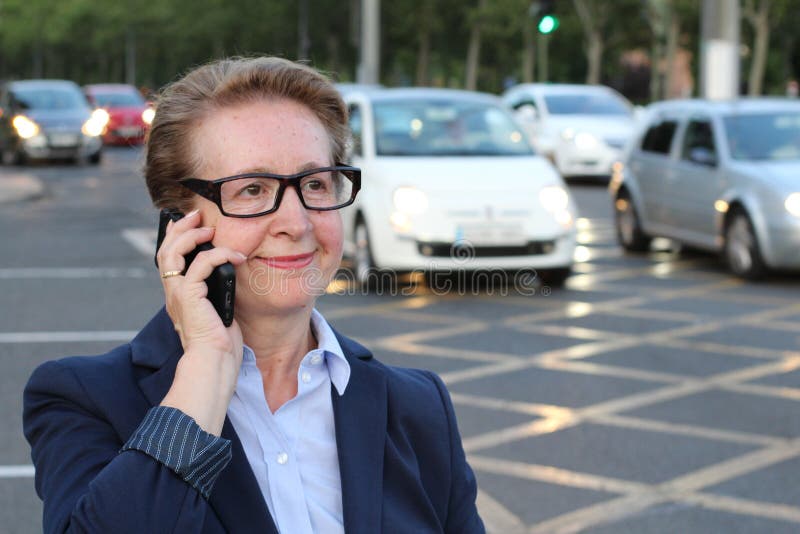 Empresaria en el teléfono móvil que camina mientras que habla en el teléfono elegante Mujer de negocios caucásica sonriente feliz imagen de archivo Empresaria en el teléfono móvil que camina mientras que habla en el teléfono elegante Mujer de negocios caucásica sonriente feliz imagen de archivo
