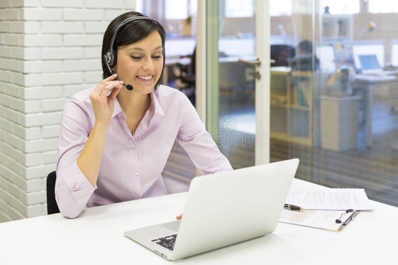 Empresaria en la oficina en el teléfono con las auriculares, Skype imágenes de archivo libres de regalías