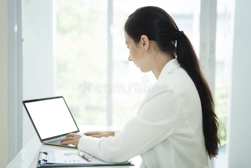 Empresaria que trabaja en el ordenador portátil con la pantalla blanca vacía imagen de archivo Empresaria que trabaja en el ordenador portátil con la pantalla blanca vacía imagen de archivo