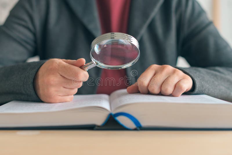 Businesswoman using magnifying glass to read the book in the office, selective focus. Businesswoman using magnifying glass to read the book in the office, selective focus