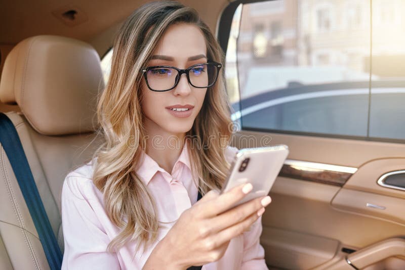 Empresaria que usa smartphone en el coche fotos de archivo libres de regalías Empresaria que usa smartphone en el coche fotos de archivo libres de regalías