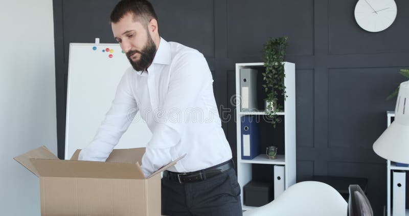 Empresario empacando sus pertenencias en una caja de cartÃ³n despuÃ©s de terminar una videollamada