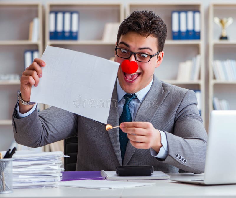 Empresario payaso quemando papeles en la oficina fotos de archivo libres de regalías