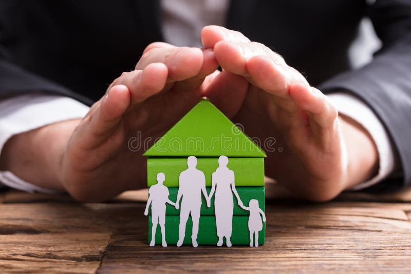 Empresario Protecting House Model y papel de la familia cortado imágenes de archivo libres de regalías Empresario Protecting House Model y papel de la familia cortado imágenes de archivo libres de regalías