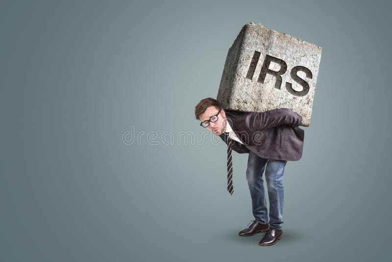 Empresario que lleva una piedra grande con las letras grabadas del IRS fotografía de archivo libre de regalías Empresario que lleva una piedra grande con las letras grabadas del IRS fotografía de archivo libre de regalías