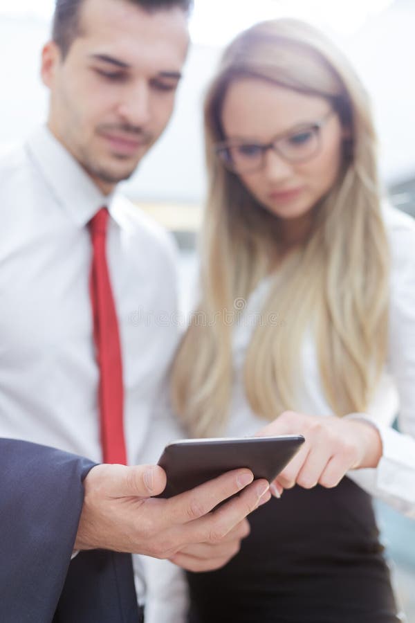 Empresarios jovenes que usan la tableta en centro de negocios imagen de archivo libre de regalías Empresarios jovenes que usan la tableta en centro de negocios imagen de archivo libre de regalías