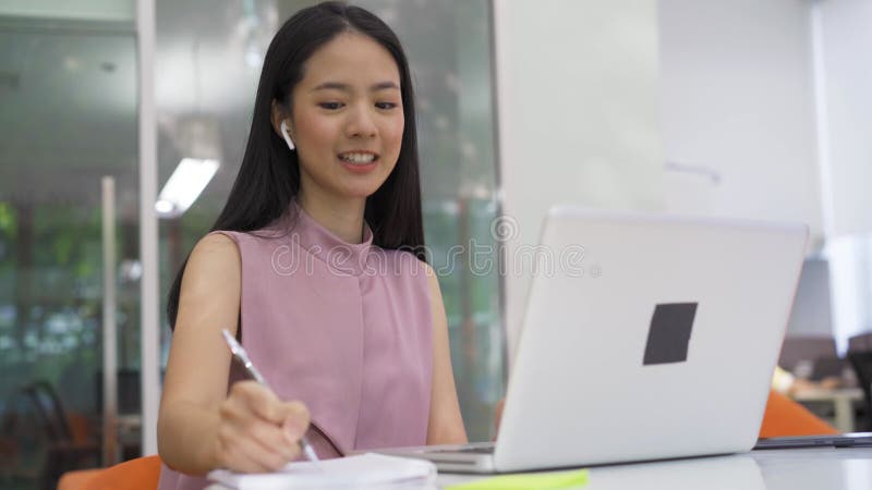 Empresária asiática animada em videocassete com colega, usando fones auriculares no escritório moderno, felicidade, negócios