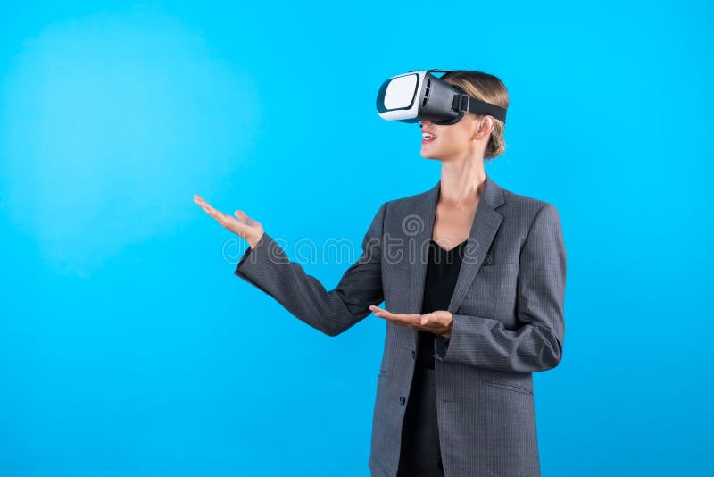 Businesswoman with VR glasses standing and present idea with confident while standing at blue background. Professional project manager wearing suit while holding something. Technology. Contraption. Businesswoman with VR glasses standing and present idea with confident while standing at blue background. Professional project manager wearing suit while holding something. Technology. Contraption.