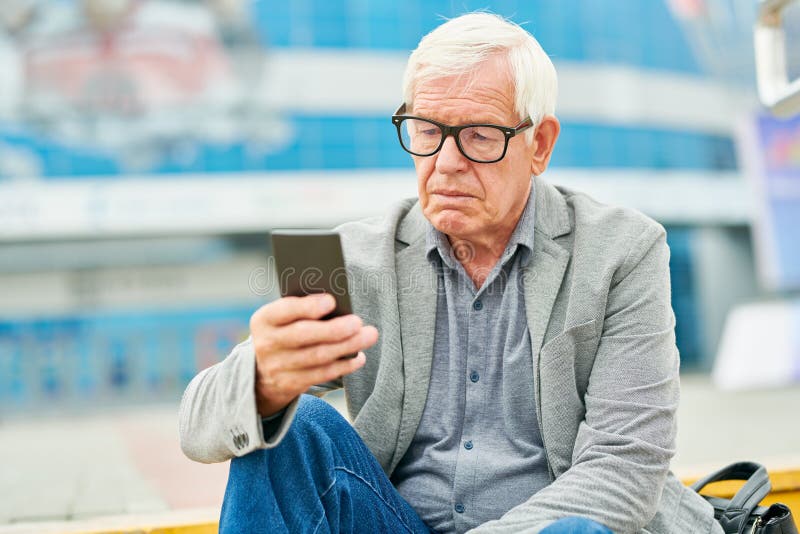 Empresário envelhecido que usa o smartphone na rua imagem de stock Empresário envelhecido que usa o smartphone na rua imagem de stock