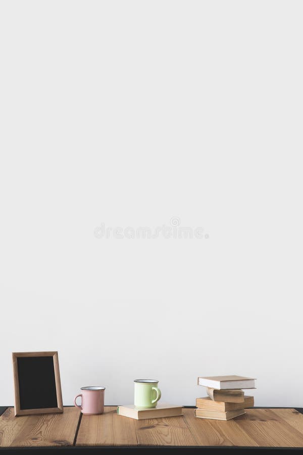 empty blackboard in frame with cups and books on wooden table on white stock image empty blackboard in frame with cups and books on wooden table on white stock image