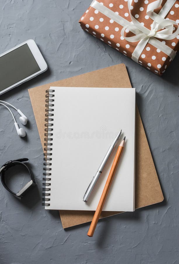 Empty blank notebook, gift box, phone on office desk top view.