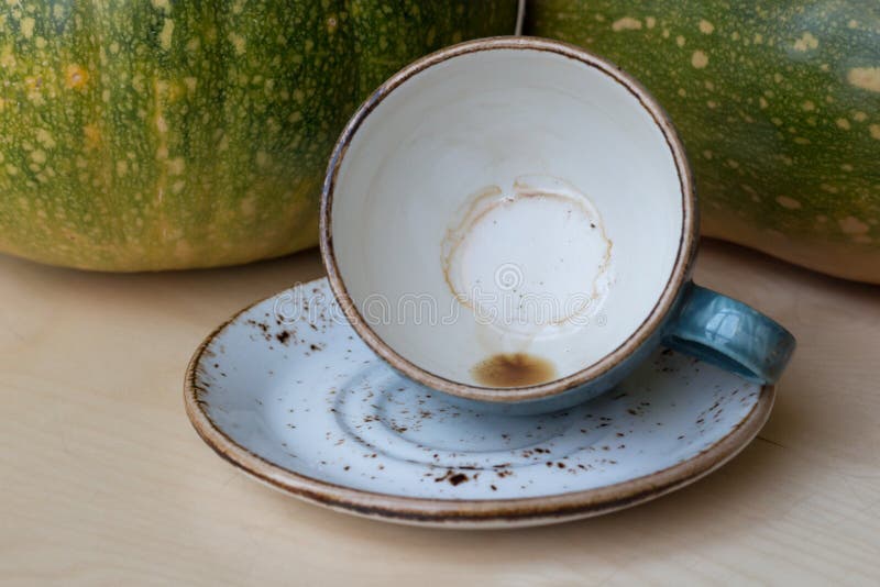 An empty blue coffee cup with traces of coffee at the bottom lies tilted on a saucer