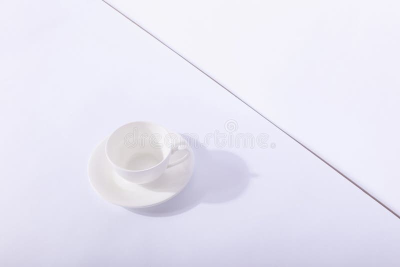 Empty ceramic cup on saucer, on white background. Hard shadow from the sun, the concept of morning