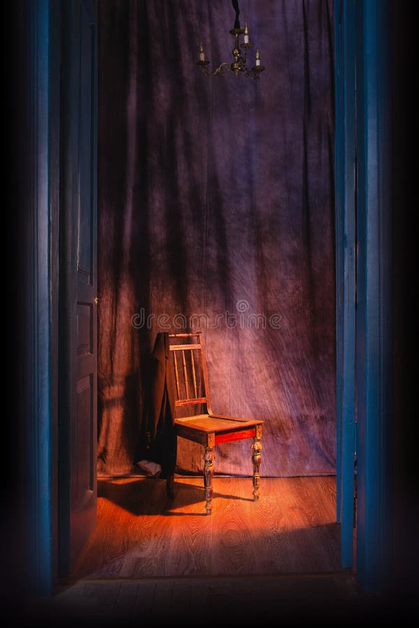 Empty chair in light behind blue massive vintage doors indoor.
