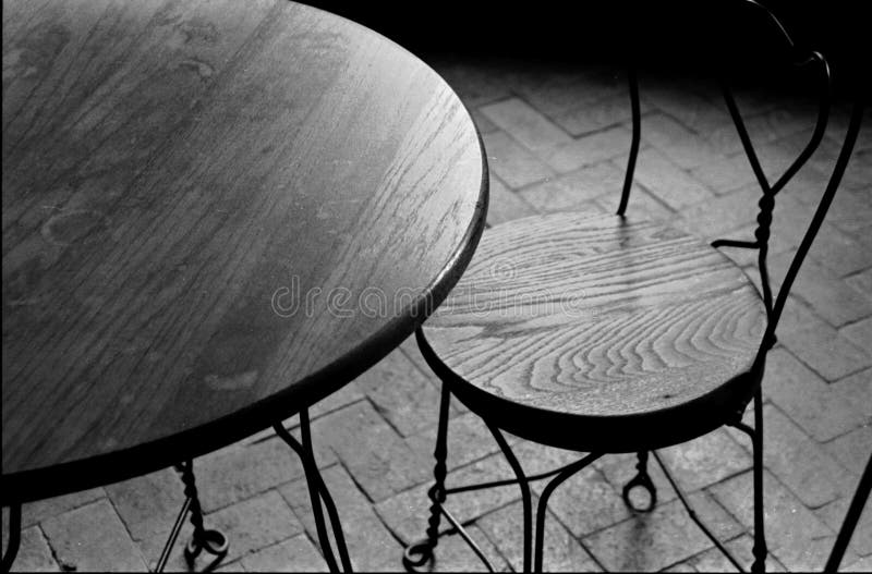 En blanco y negro imagen de estructurado mesa una silla sobre el ladrillo piso.