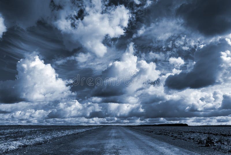 Empty country road under dramatic cloudy sky royalty free stock photography
