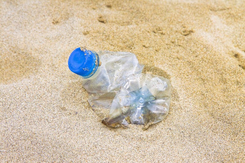 Empty Crumpled Plastic Bottle of Water Abandoned on the Beach Stock