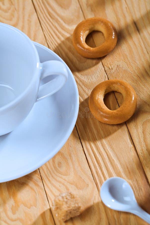 Empty cup with spoon and cookie on table