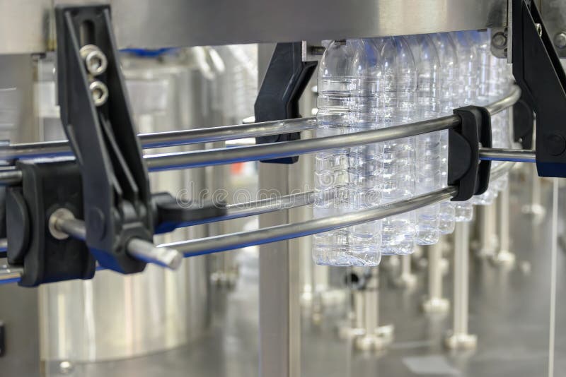 The empty drinking water bottles hanging on the conveyor belt for filling process. The hi-technology of drinking water manufacturing process