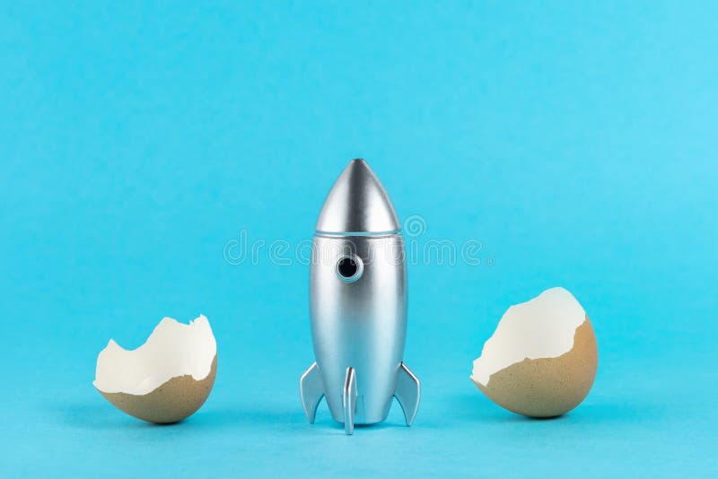 Empty eggshell with a silver rocket on pastel blue background. Minimal Easter holiday concept stock images