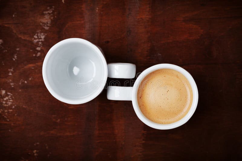 Empty and full cup of fresh coffee on rustic wooden table, benefits and harms of coffee concept royalty free stock photography