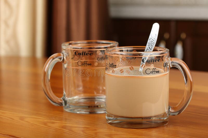 Empty and full transparent glass cup with coffee and milk on a table