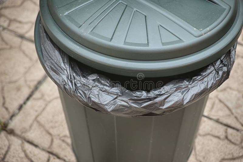 Empty green trash can with garbage bag inside stock photography