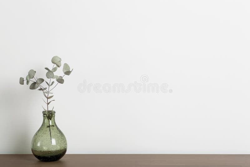 Empty home desk table background. Wooden table with a vase and a plant against a white wall in the living room of a home