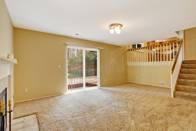 Empty house interior. View of empty living room with walkout deck and staircase to kitchen. Empty house interior. View of empty living room with walkout deck and staircase to kitchen