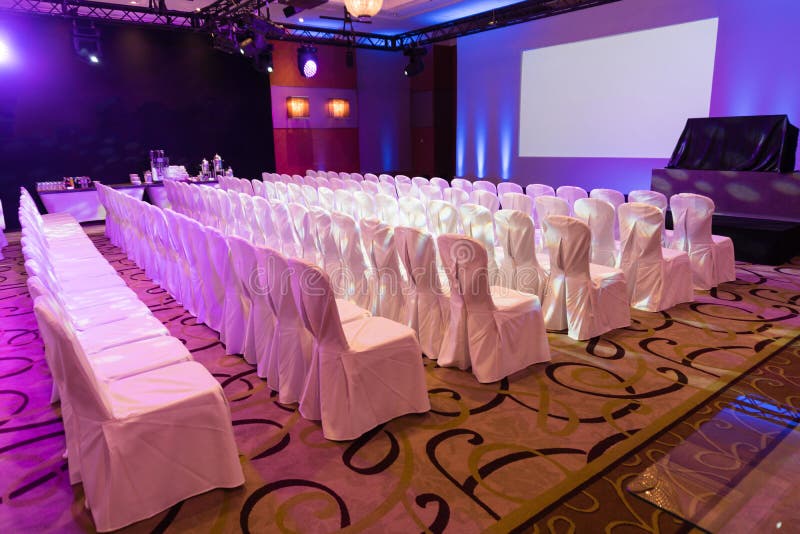Empty interior of luxury conference hall or seminar room with projector screen, white chairs