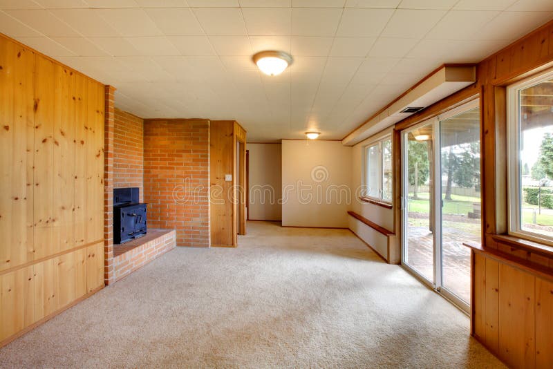 Empty living room with wood panel walls and cast iron fireplace