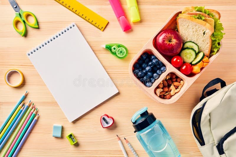 Top down view of school supplies and lunch on a light background