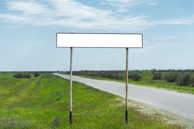 Empty old road sign for the name of a city or village populated area near the road in the countryside against a blue sky