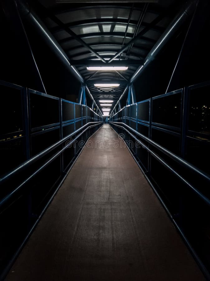 Empty pedestrian walkway illuminated with fluorescent tubes at night. Metallic structure over a road royalty free stock photo Empty pedestrian walkway illuminated with fluorescent tubes at night. Metallic structure over a road royalty free stock photo