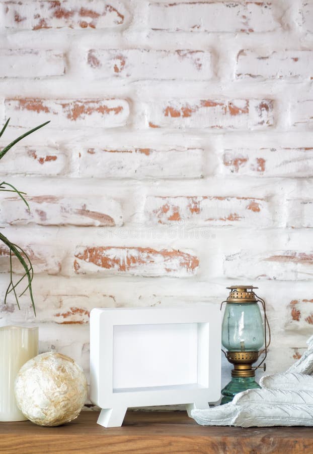 Empty photo frame on shelf with decoration over whirte brick stock image